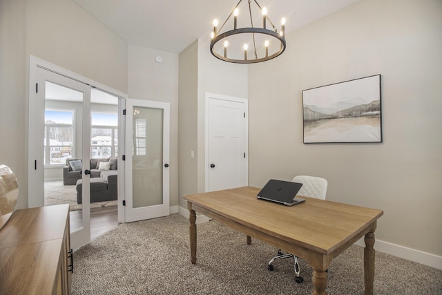 carpeted office with french doors and a chandelier