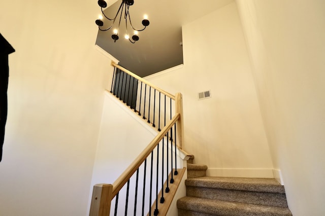 stairway with a notable chandelier, crown molding, and a high ceiling