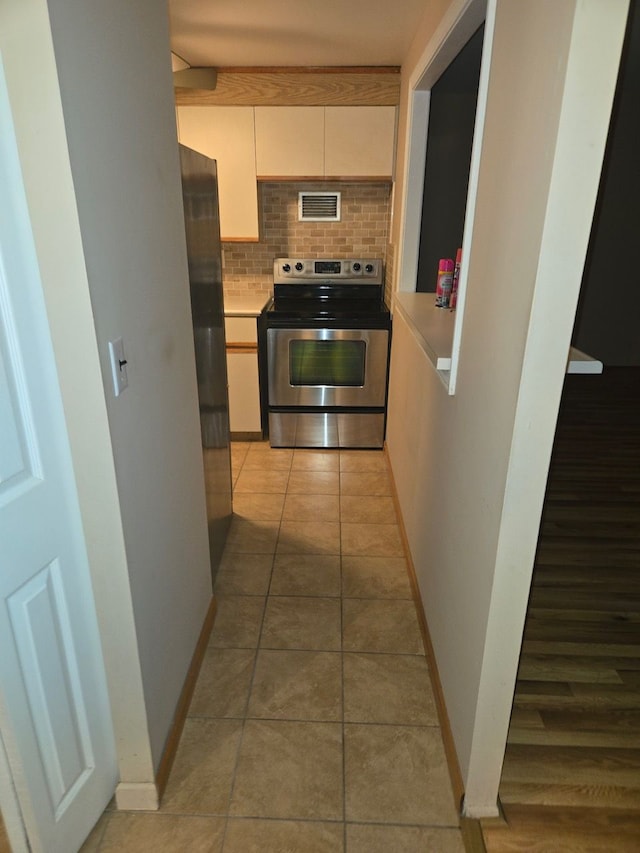 kitchen with white cabinetry, stainless steel appliances, tasteful backsplash, and light tile patterned floors