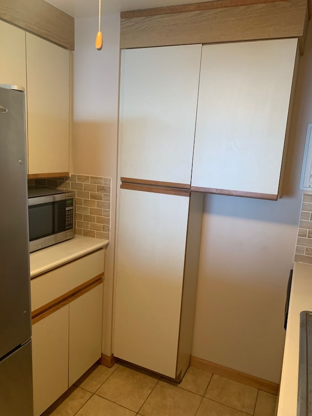 kitchen featuring tasteful backsplash, pendant lighting, light tile patterned flooring, and appliances with stainless steel finishes