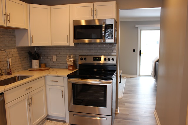 kitchen featuring white cabinets, decorative backsplash, sink, and appliances with stainless steel finishes