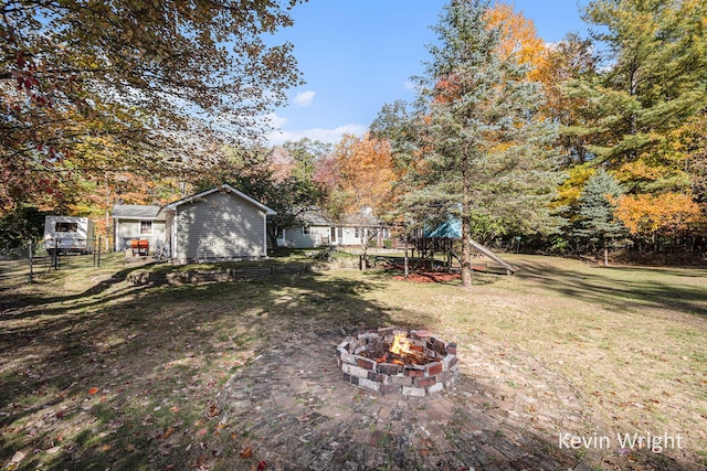 view of yard featuring a fire pit, an outbuilding, and a playground
