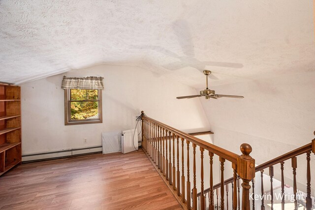 additional living space with hardwood / wood-style floors, lofted ceiling, a baseboard heating unit, ceiling fan, and a textured ceiling