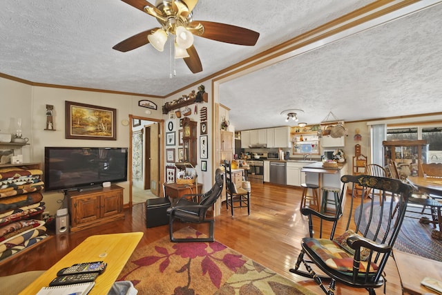 living room featuring a textured ceiling, light wood-type flooring, and ornamental molding