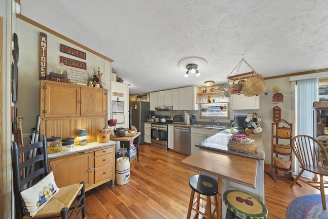 kitchen featuring light stone countertops, stainless steel appliances, sink, wood-type flooring, and white cabinetry