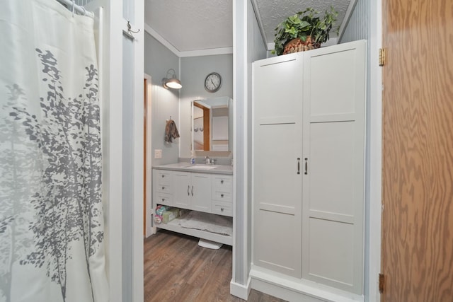 bathroom with hardwood / wood-style floors, vanity, crown molding, a shower with shower curtain, and a textured ceiling