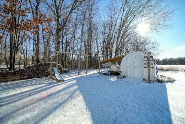 snowy yard featuring a storage shed