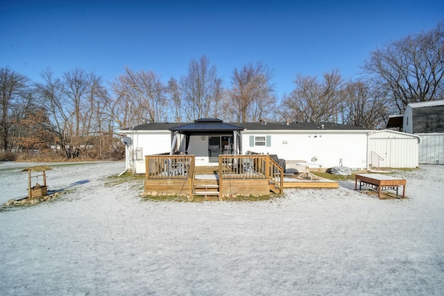 snow covered rear of property with a gazebo, a storage shed, and a deck