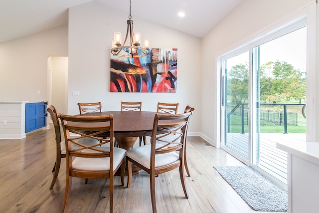 dining space with vaulted ceiling, wood-type flooring, and an inviting chandelier