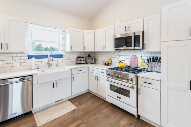 kitchen with sink, dark hardwood / wood-style flooring, vaulted ceiling, white cabinets, and appliances with stainless steel finishes