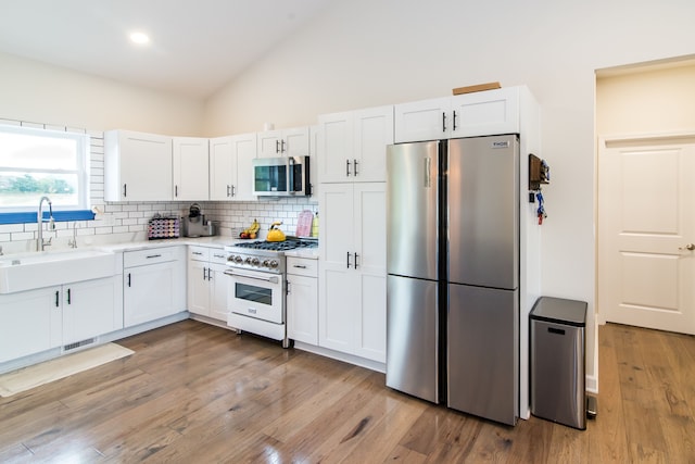 kitchen with white cabinetry, sink, backsplash, appliances with stainless steel finishes, and light wood-type flooring