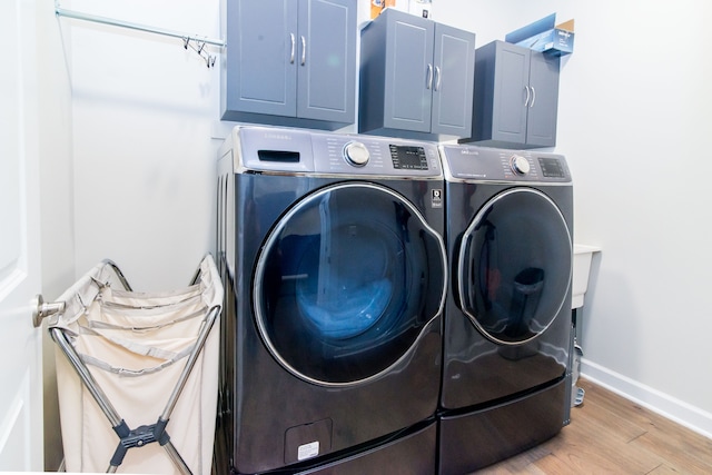 laundry area with washer and clothes dryer, cabinets, and light wood-type flooring