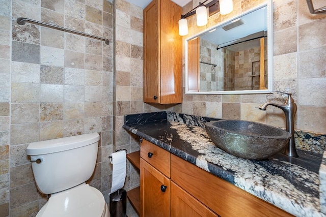 bathroom with vanity, toilet, and tile walls