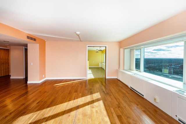 spare room featuring a chandelier, light hardwood / wood-style flooring, and baseboard heating