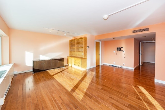 unfurnished living room featuring hardwood / wood-style floors and rail lighting