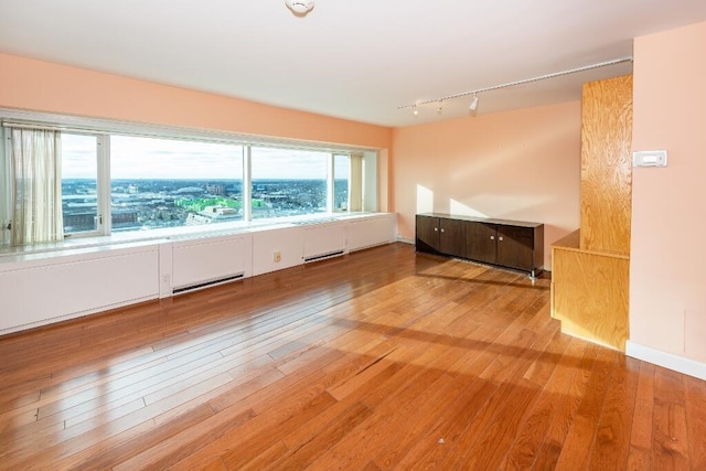 unfurnished room featuring hardwood / wood-style floors and rail lighting