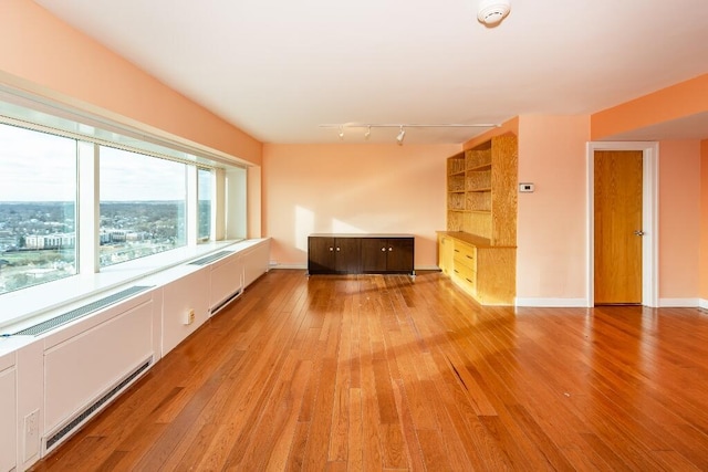 unfurnished living room with track lighting and light wood-type flooring