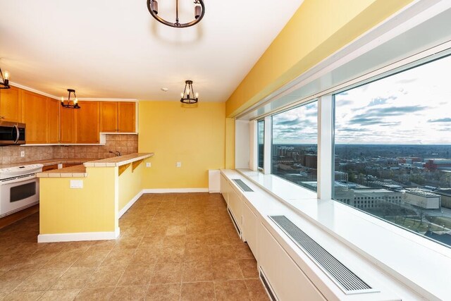 kitchen with white electric range oven, kitchen peninsula, tile countertops, pendant lighting, and decorative backsplash