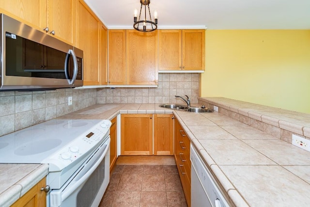 kitchen with tile countertops, white appliances, an inviting chandelier, sink, and tasteful backsplash