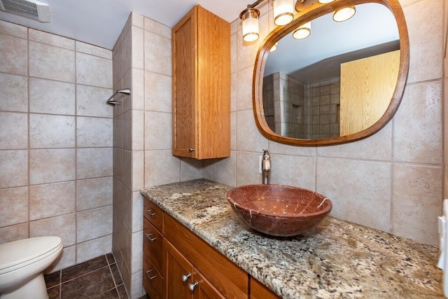 bathroom featuring vanity, toilet, tile walls, and backsplash