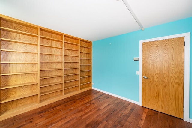 spare room with built in features and dark wood-type flooring