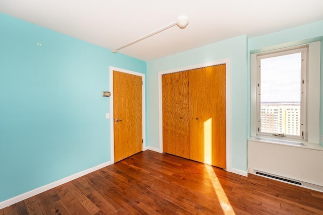 unfurnished bedroom featuring a closet and dark wood-type flooring