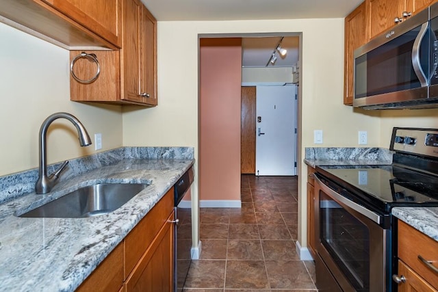 kitchen with light stone counters, sink, stainless steel appliances, and track lighting