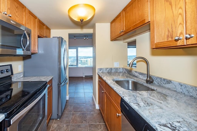 kitchen featuring appliances with stainless steel finishes, light stone counters, dark tile patterned floors, and sink