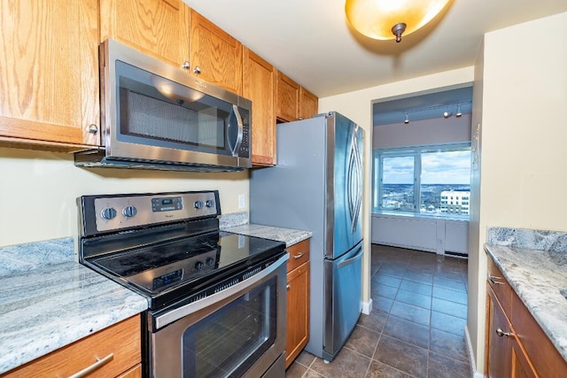 kitchen with stainless steel appliances, light stone counters, and dark tile patterned floors