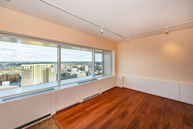 unfurnished room with rail lighting and dark wood-type flooring