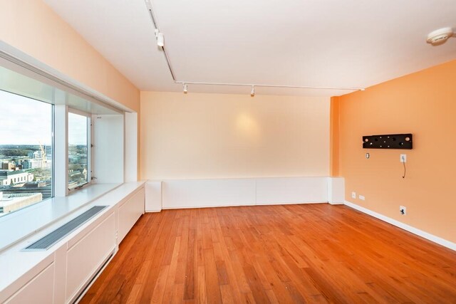 unfurnished room with rail lighting and light hardwood / wood-style floors