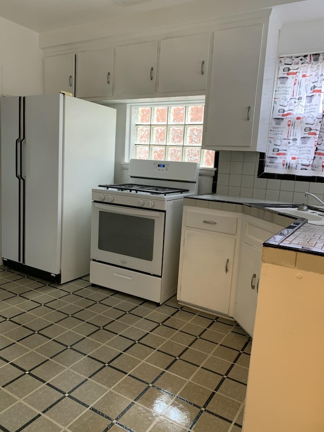 kitchen featuring decorative backsplash, tile counters, white cabinets, and white appliances