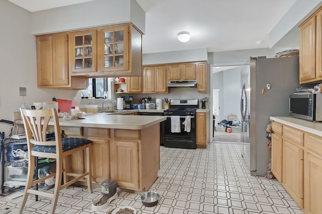 kitchen featuring a breakfast bar, light brown cabinets, sink, appliances with stainless steel finishes, and kitchen peninsula