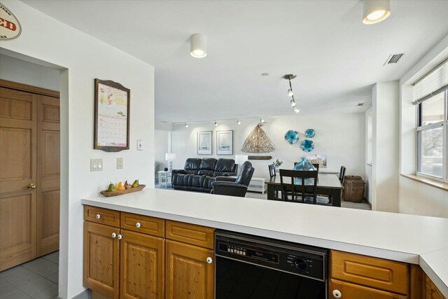 kitchen with kitchen peninsula, black dishwasher, and light tile patterned flooring
