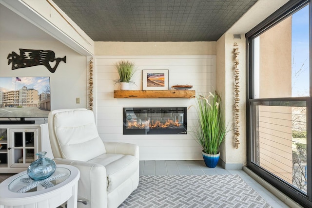 living area featuring tile patterned floors and wood walls