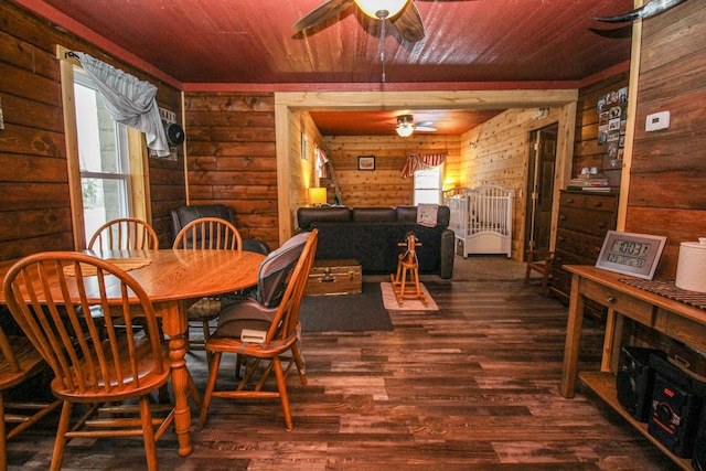 dining room featuring ceiling fan, log walls, and dark wood-type flooring