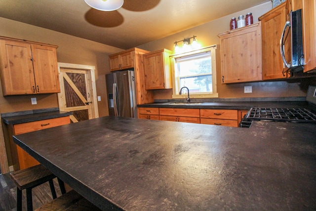 kitchen featuring a breakfast bar, sink, stainless steel refrigerator with ice dispenser, ceiling fan, and range