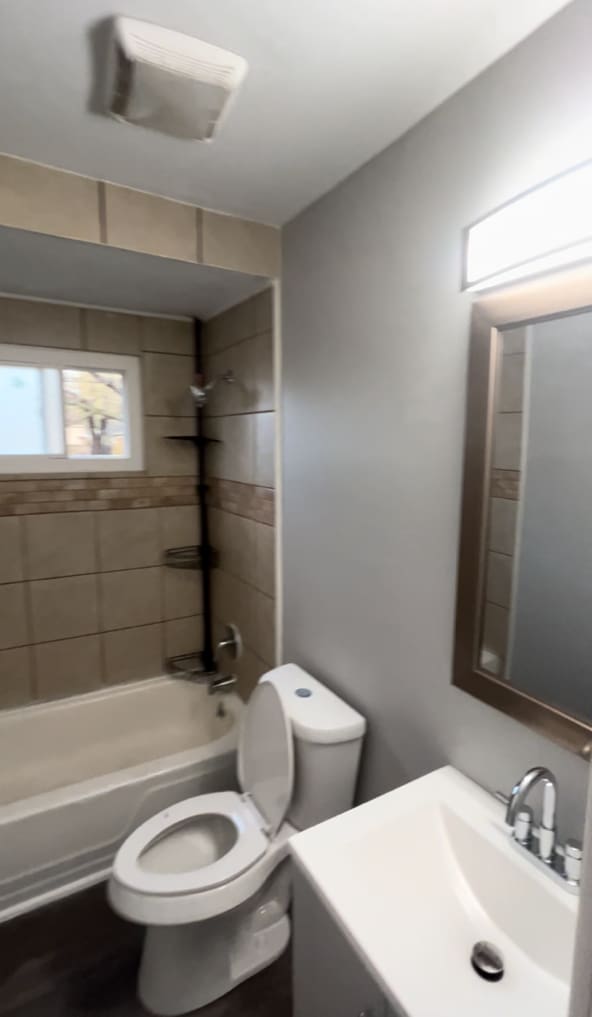 full bathroom with vanity, tiled shower / bath combo, and toilet