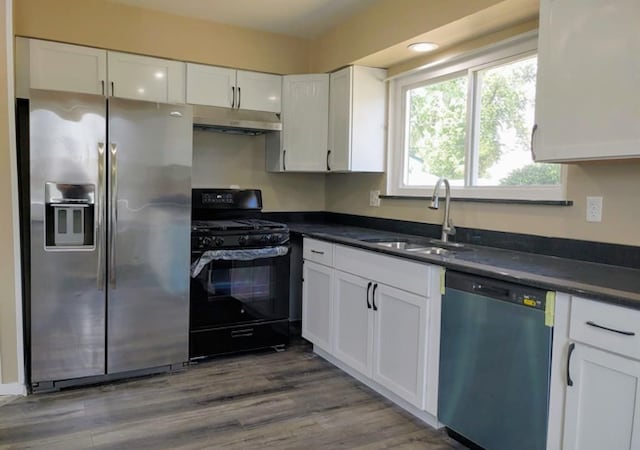 kitchen with white cabinets, appliances with stainless steel finishes, wood-type flooring, and sink