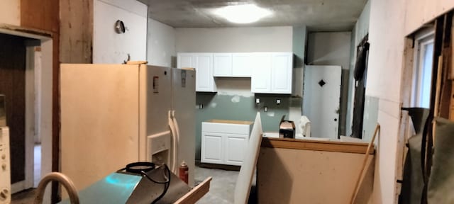 kitchen featuring white cabinets and white fridge with ice dispenser