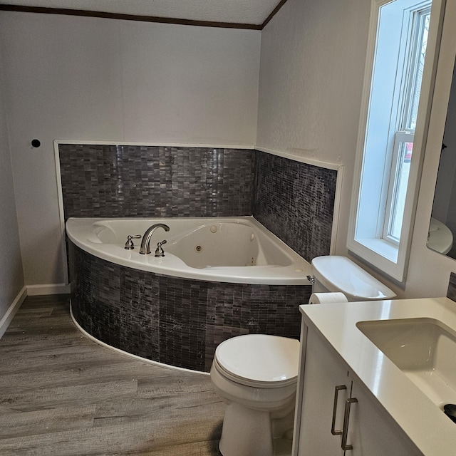 bathroom with vanity, crown molding, hardwood / wood-style floors, tiled bath, and toilet