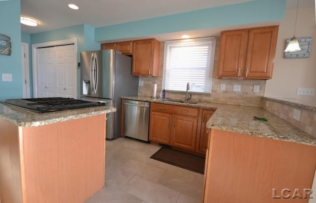 kitchen with pendant lighting, backsplash, sink, and appliances with stainless steel finishes