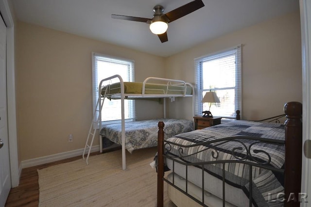 bedroom featuring ceiling fan, light wood-type flooring, and multiple windows