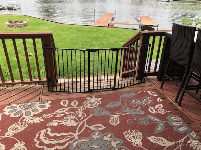 deck with a water view, a dock, and a lawn