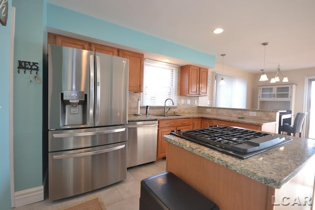 kitchen featuring pendant lighting, a center island, sink, light tile patterned floors, and stainless steel appliances