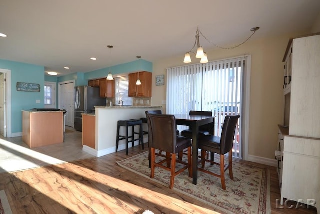 dining space with light hardwood / wood-style floors and an inviting chandelier