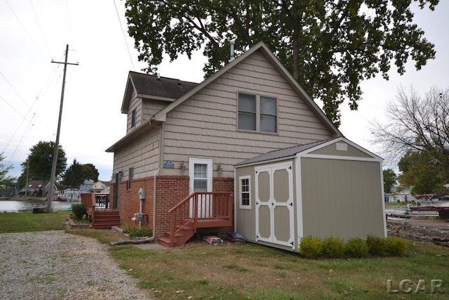 rear view of house featuring a storage unit and a lawn