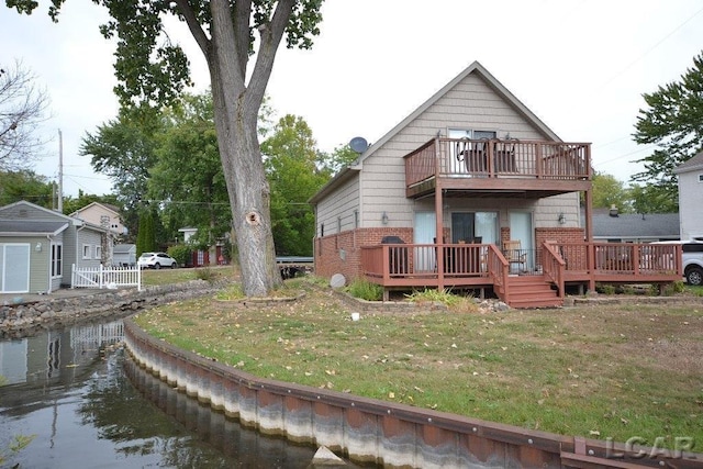 rear view of house featuring a lawn and a balcony