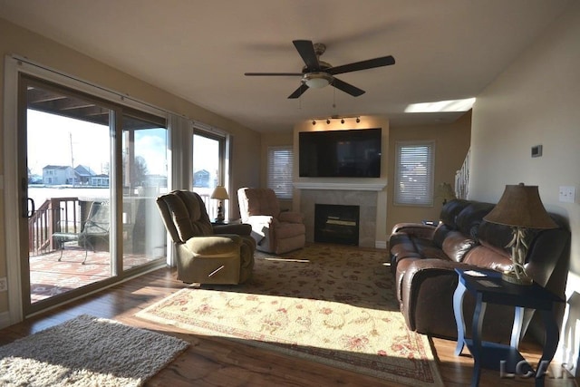 living room featuring hardwood / wood-style floors, ceiling fan, and a tiled fireplace