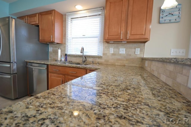 kitchen with light stone countertops, decorative backsplash, stainless steel appliances, and sink